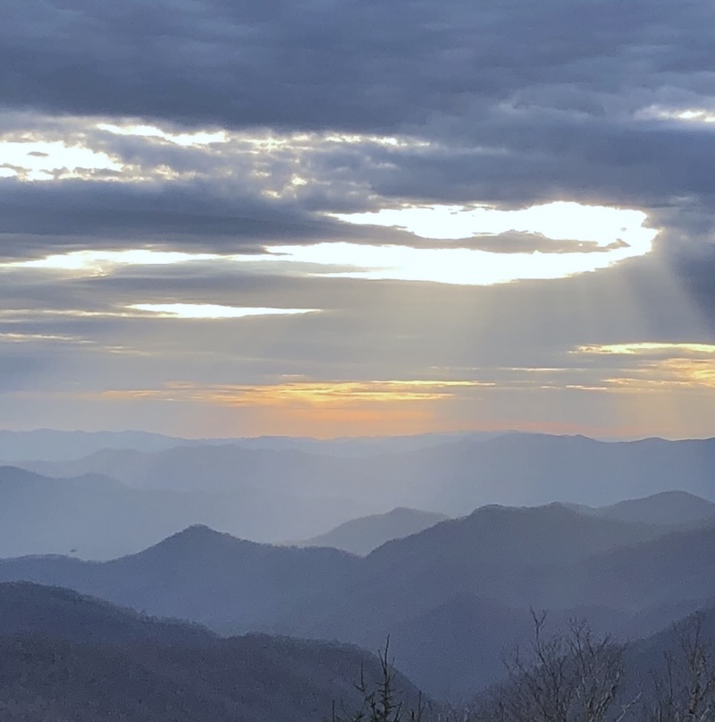 Layered mountain ridges at sunset in Western North Carolina with light breaking through the clouds